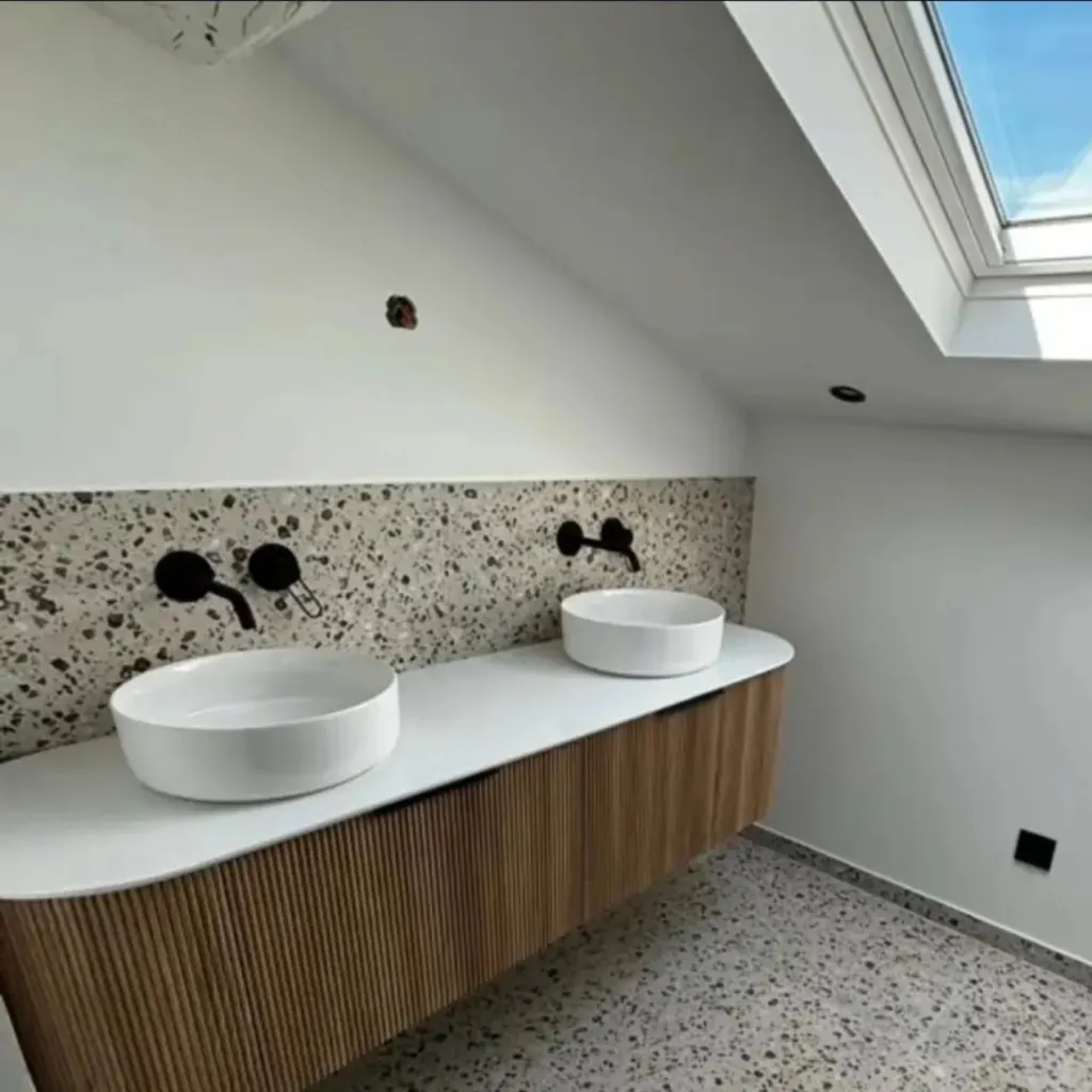 Salle de bain avec mur noir veiné rétroéclairé, paroi de douche à profils laiton, WC et meuble vasque suspendu.