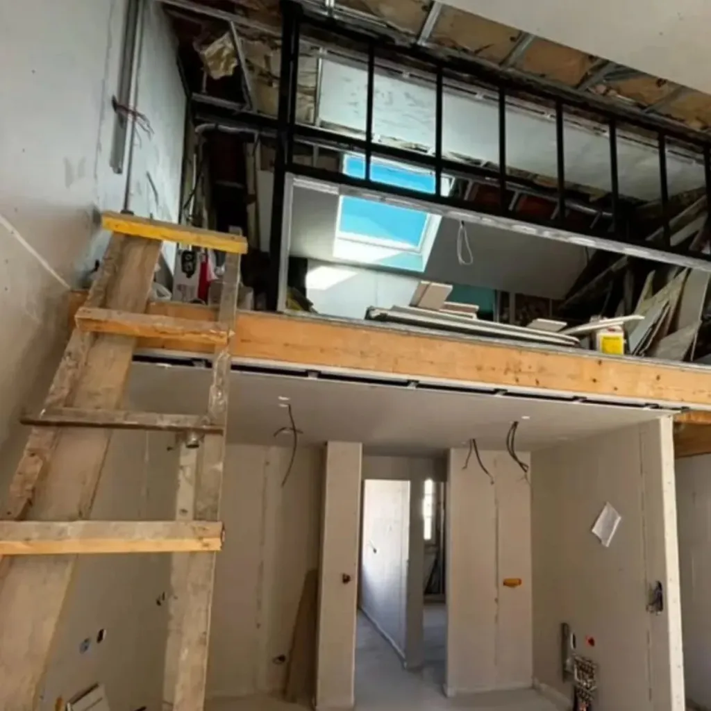 Chantier de rénovation avec ossature métallique, cloisons en plaques de plâtre et plancher bois sous les combles.