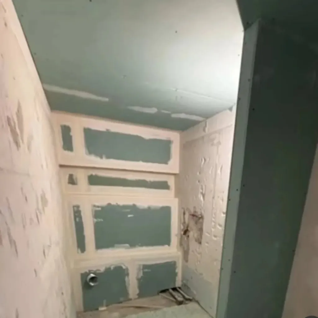 Zone de douche en cours de préparation avec plaques hydrofuges vertes, enduit de jointoiement et évacuation visible.