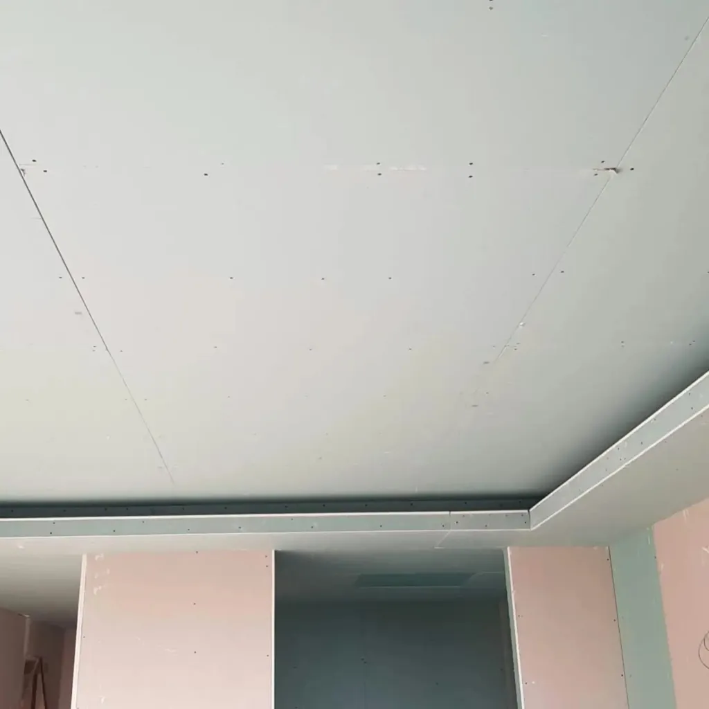 Grande surface de plafond en plaques de plâtre vissées avec retombée en bordure, avant bandes à joints.