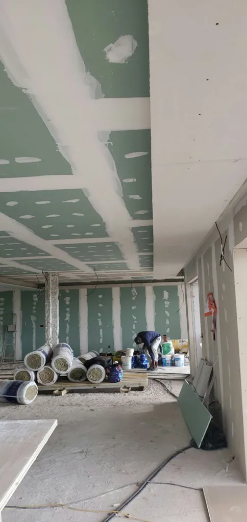 Grand plateau en cours de cloisonnement en plaques, rouleaux d'isolant au sol.