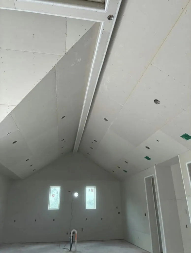 Pièce sous combles dont rampants et plafond sont habillés de plaques de plâtre, petites fenêtres.
