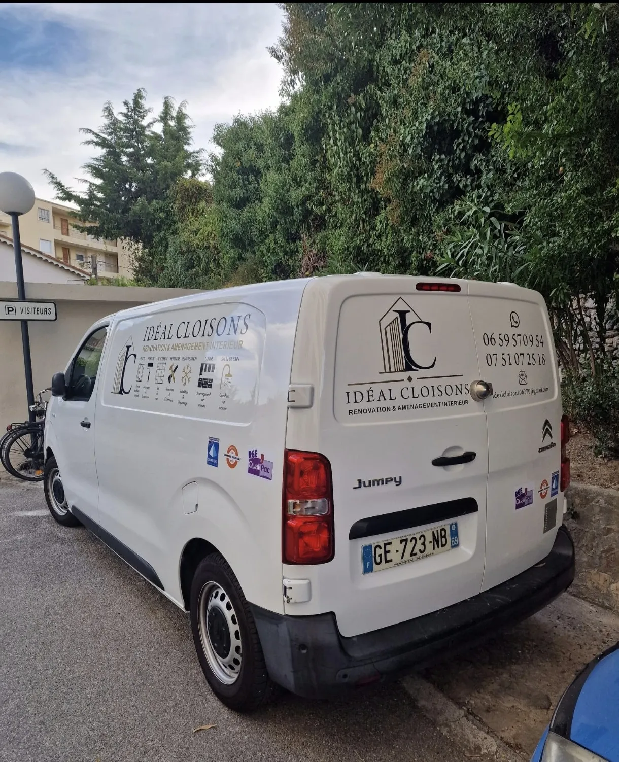 White Citroën Jumpy van with Idéal Cloisons branding parked by trees and a P Visiteurs sign